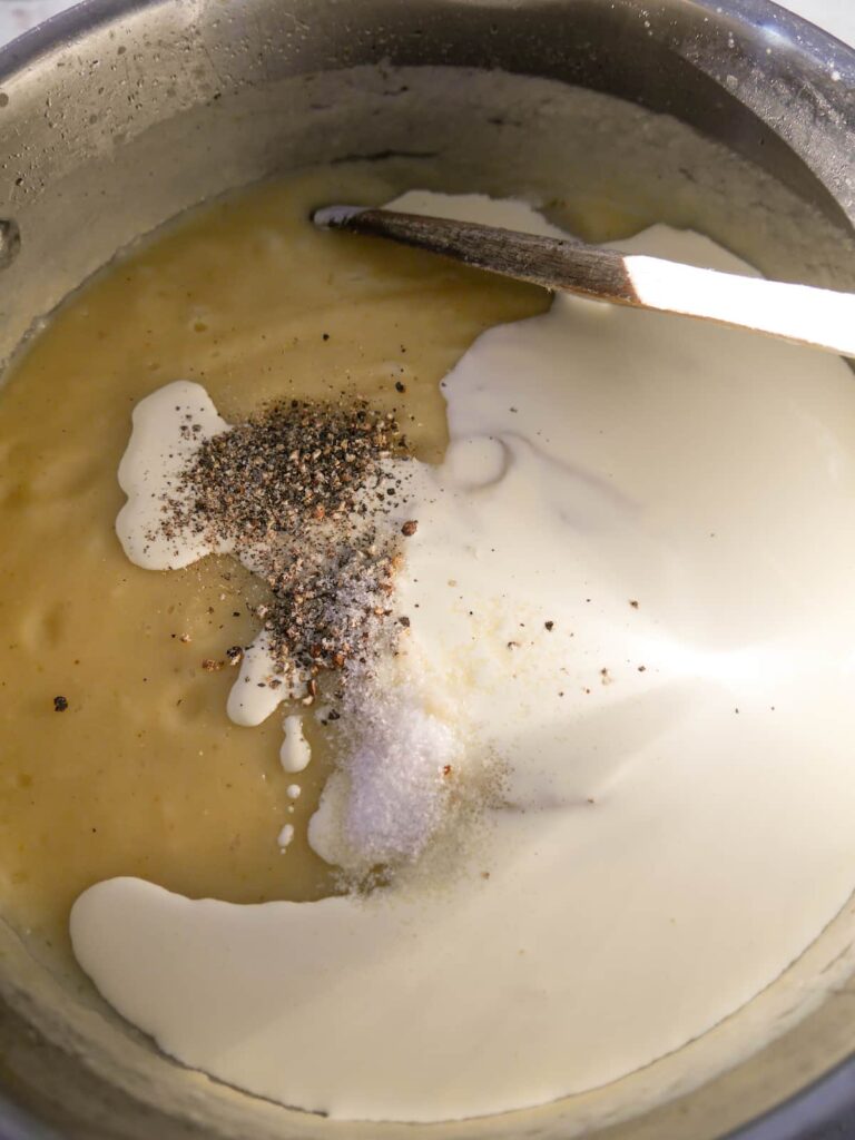 A saucepan of pureed parsnip soup with added double cream and seasoning.