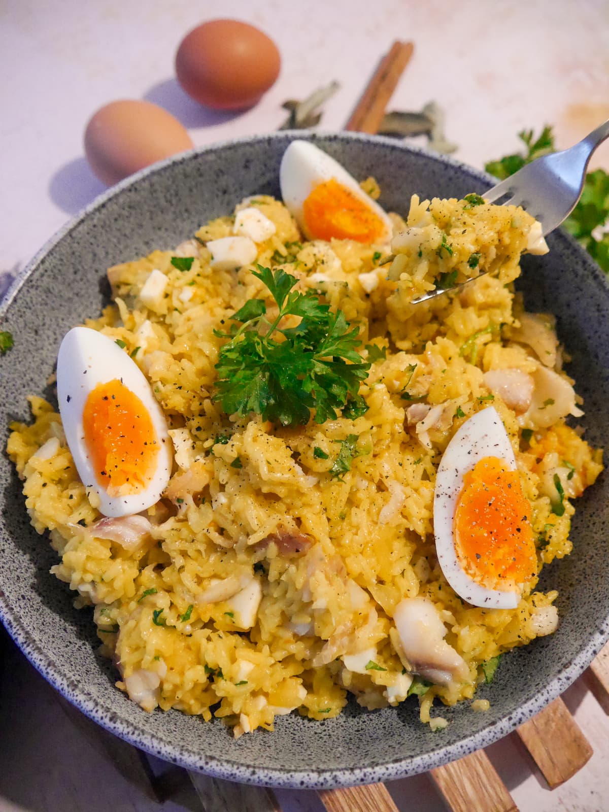 A bowl of smoked haddock kedgeree garnished with wedges of boiled egg and fresh parsley.