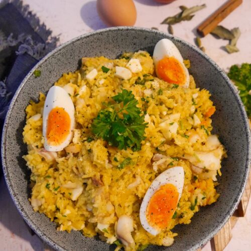 A bowl of smoked haddock kedgeree garnished with wedges of boiled egg and fresh parsley.