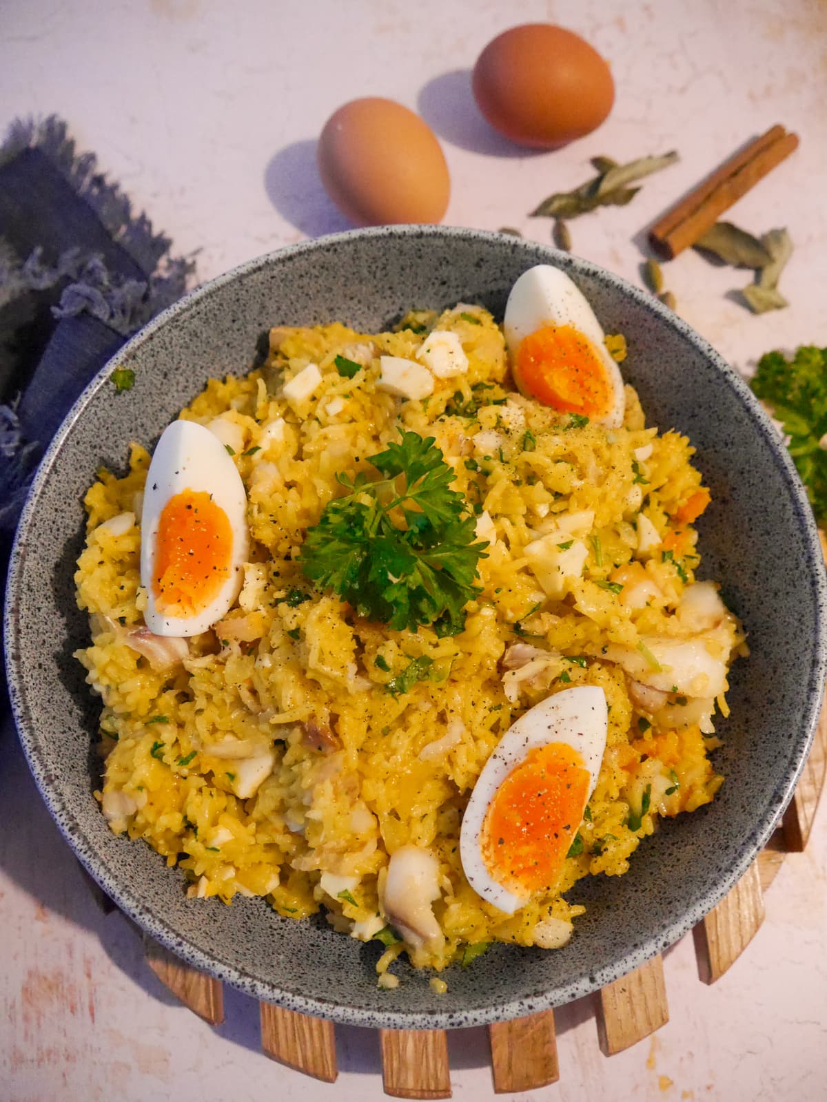 A bowl of smoked haddock kedgeree garnished with wedges of boiled egg and fresh parsley.