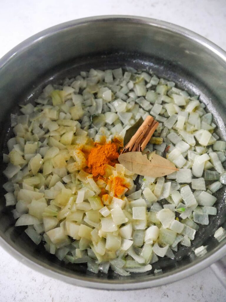 A frying pan of sautéed onion with added whole and dried spices.