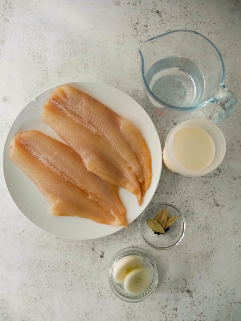 Poached smoked haddock recipe ingredients set out in individual bowls.