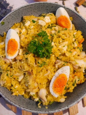 A bowl of smoked haddock kedgeree garnished with wedges of boiled egg and fresh parsley.