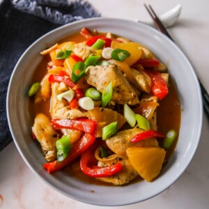 A bowl of sweet and sour chicken with stir-fried vegetables.