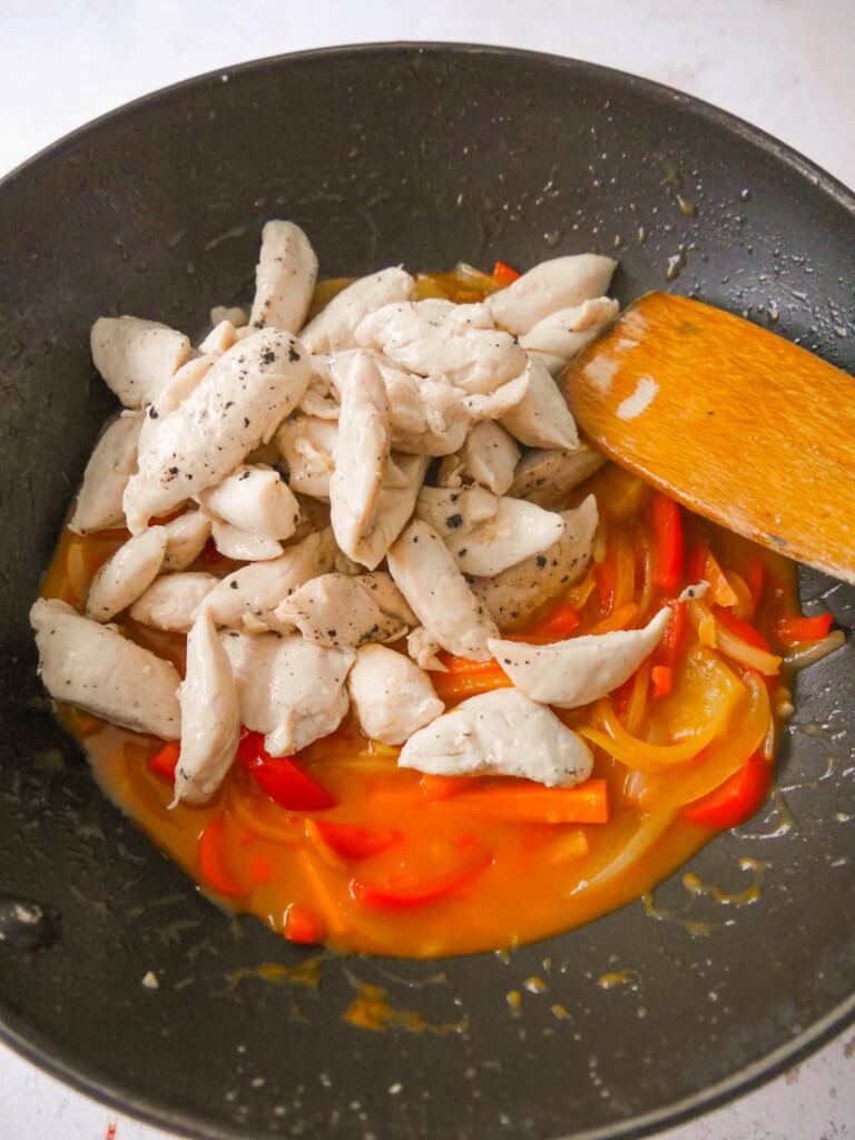 A wok with sweet and sour vegetables in sauce with added cooked chicken.