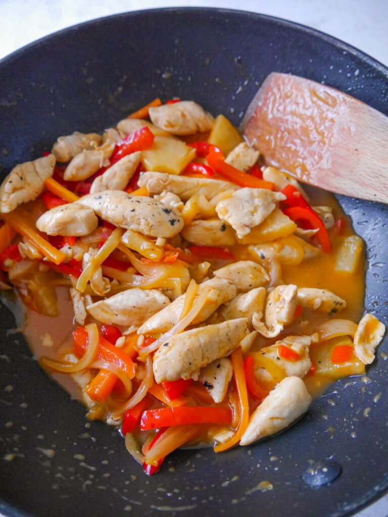 A wok filled with sweet and sour chicken.