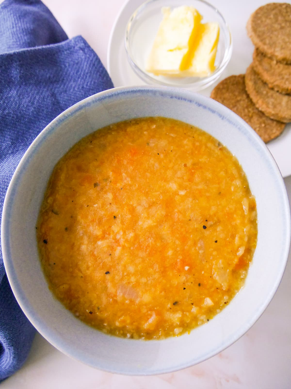 A soup bowl filled with Scottish yellow split pea soup, served with oatcakes and butter.
