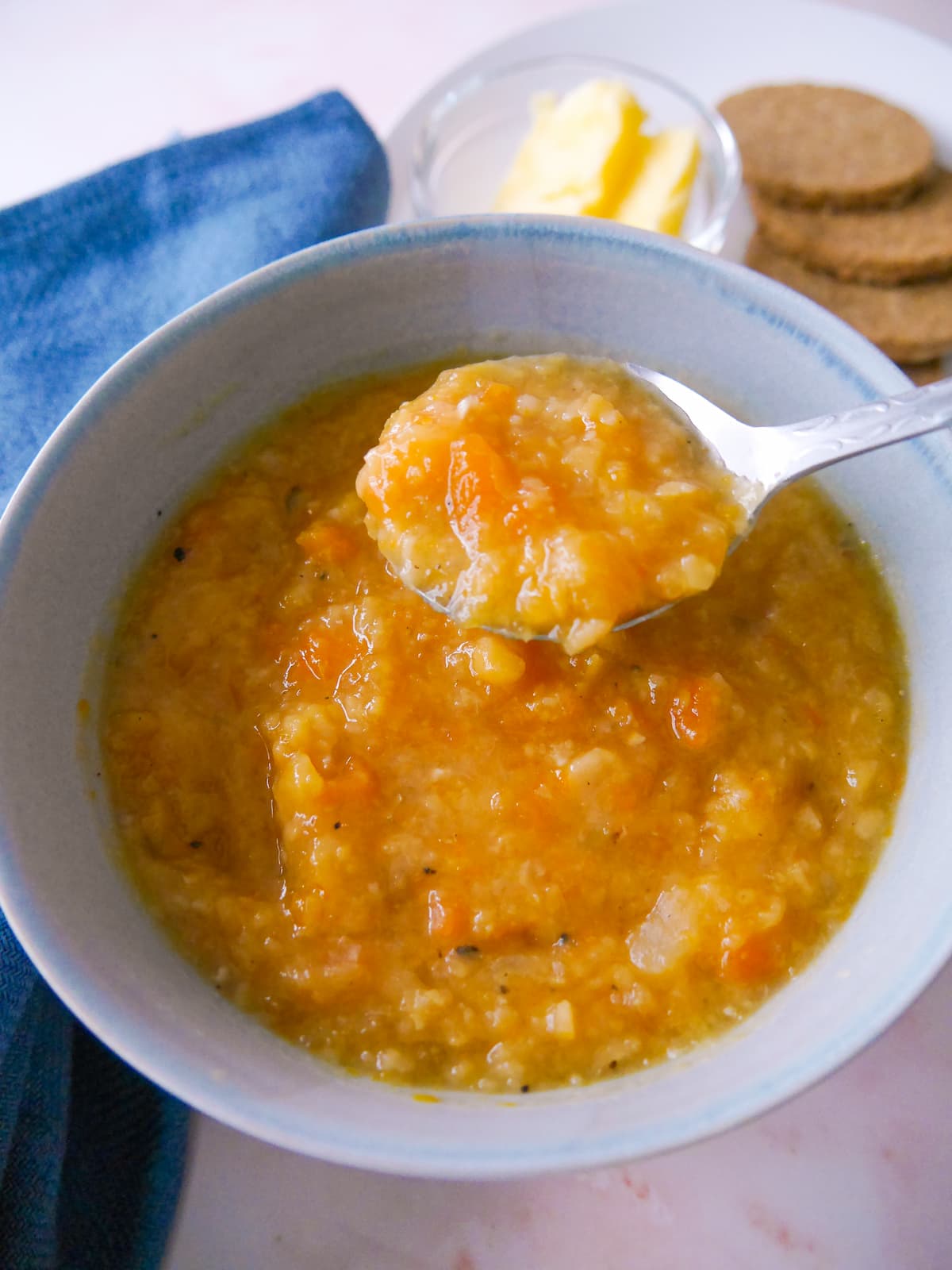 A soup bowl filled with Scottish yellow split pea soup, served with oatcakes and butter.