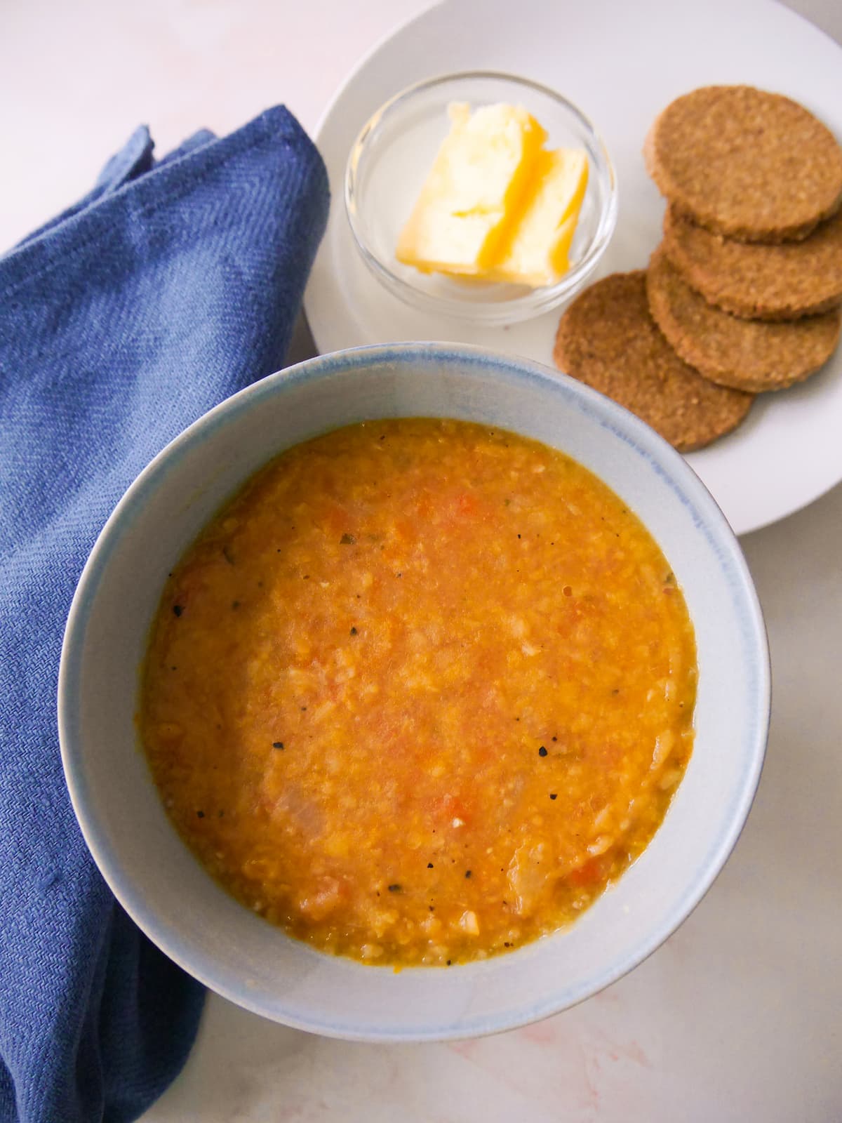 A soup bowl filled with Scottish yellow split pea soup, served with oatcakes and butter.