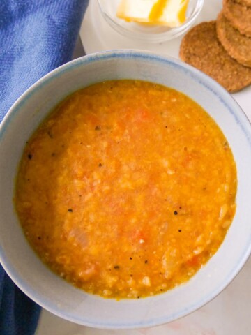 A soup bowl filled with Scottish yellow split pea soup, served with oatcakes and butter.