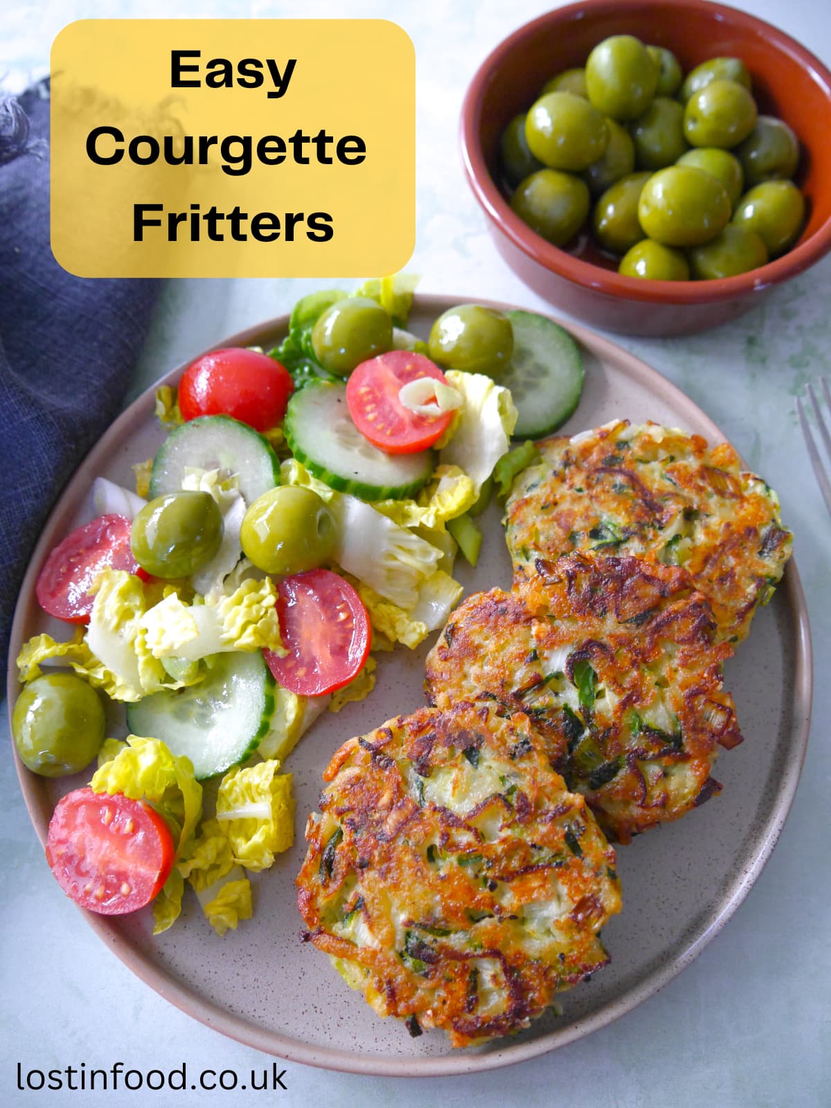 Pinnable image with recipe title and plate with three courgette fritters and a side salad.