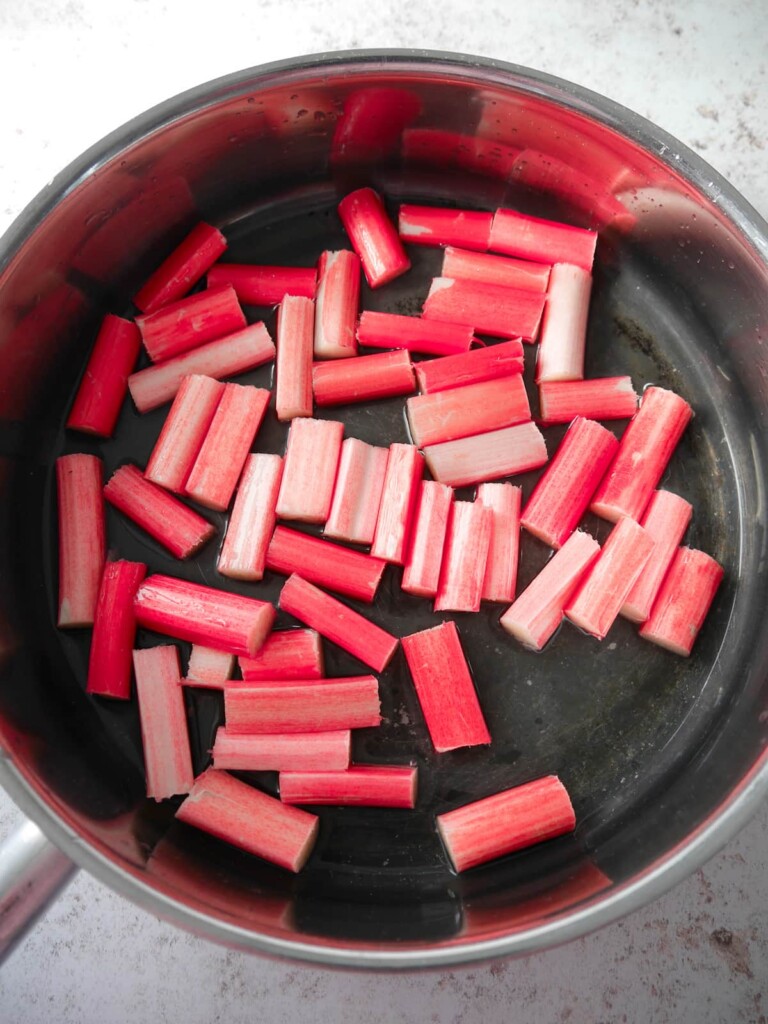 A large pan filled with short batons of rhubarb with added water and vanilla extract.