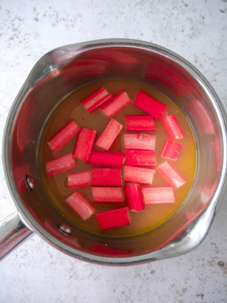 A saucepan with batons of rhubarb and fresh orange juice.