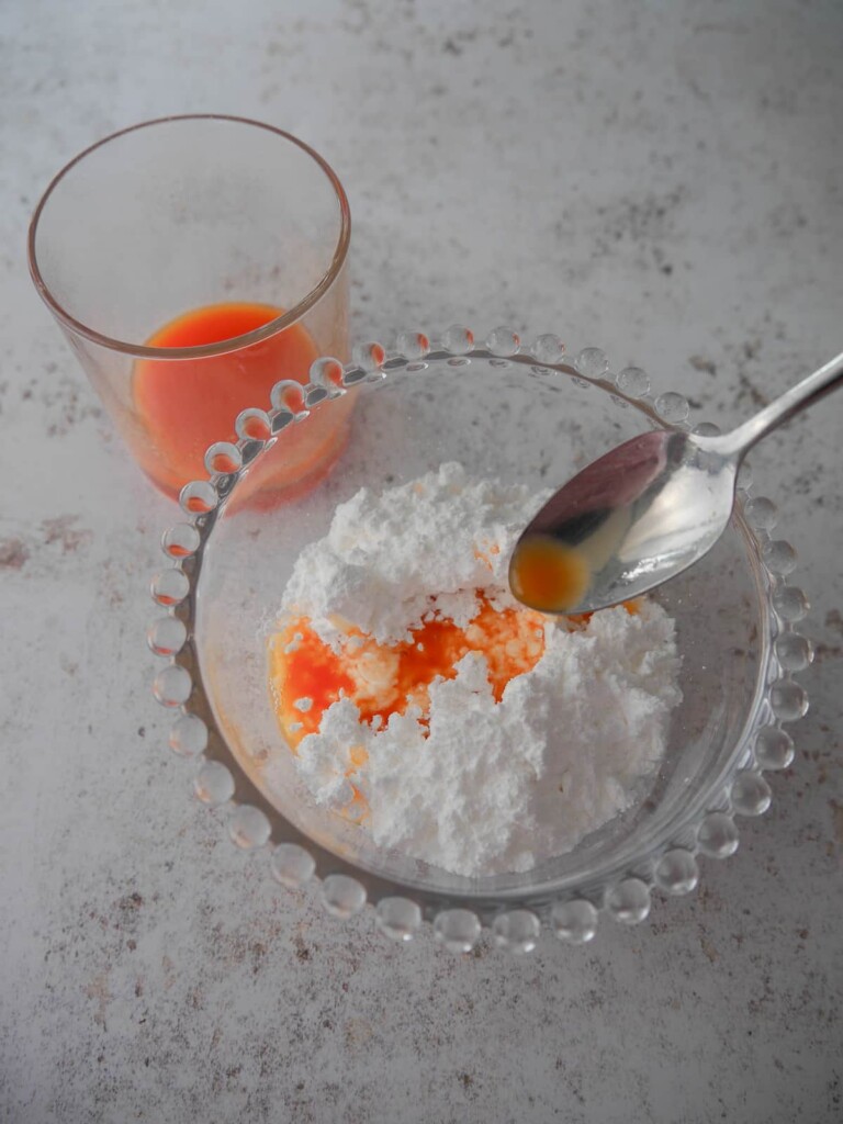 Rhubarb and orange juice being spooned into a bowl of icing sugar (powdered sugar).