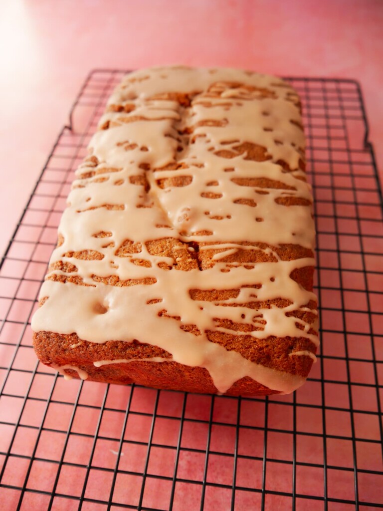 Rhubarb and orange loaf cake set on a wire cooling rack.