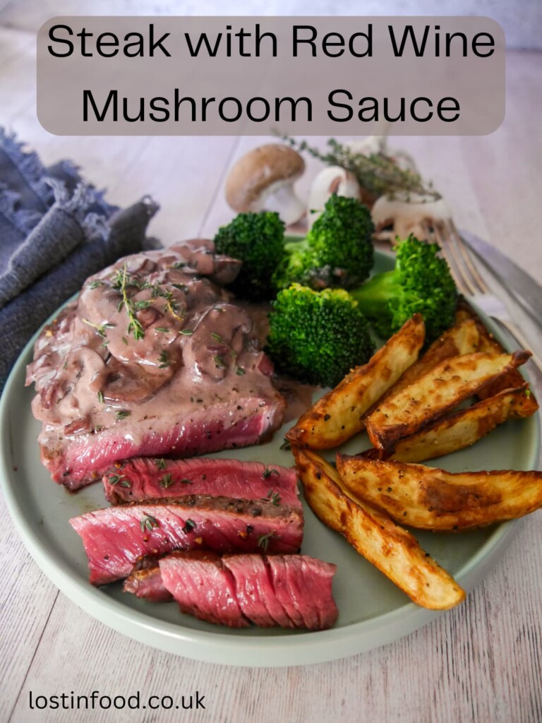 Pinnable image with recipe title and a plate of medium rare sirloin steak, topped with a red wine mushroom sauce and served with a side of potato wedges and steamed broccoli.
