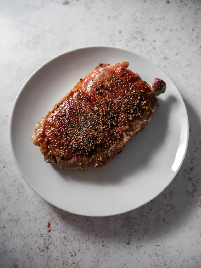 Pan fried sirloin steak resting on a warm plate.