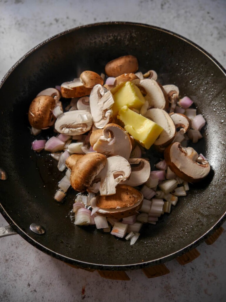 A frying pan with leftover steak juices, with added mushrooms, shallot, garlic and butter.
