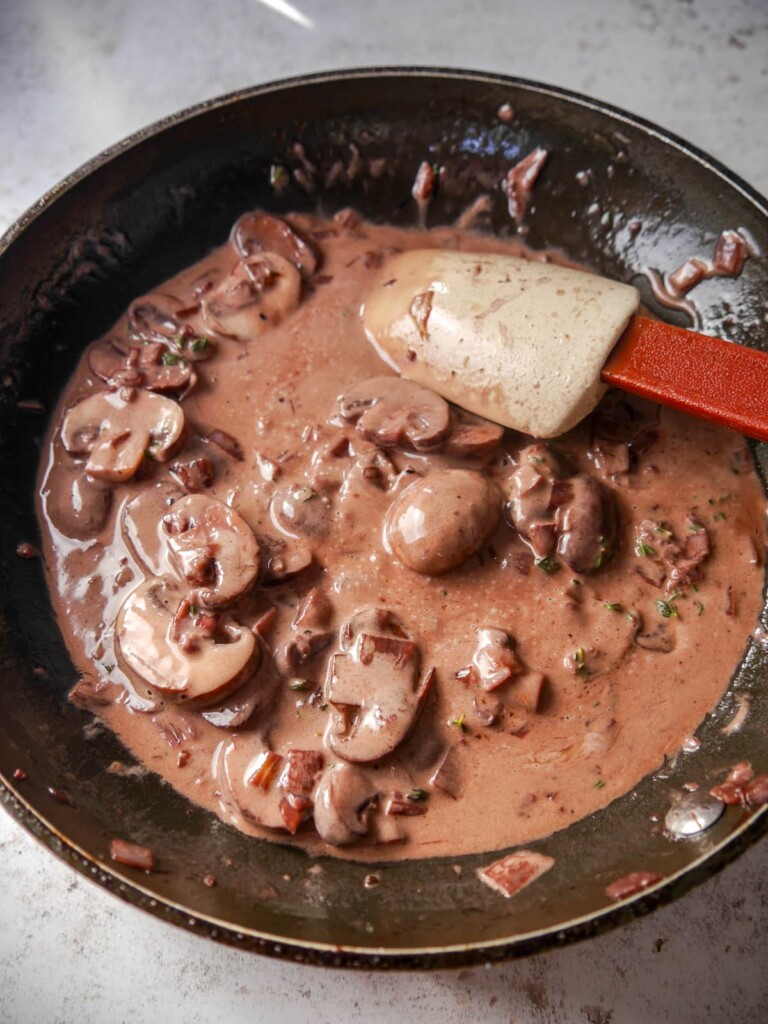 A frying pan of creamy red wine and mushroom sauce.