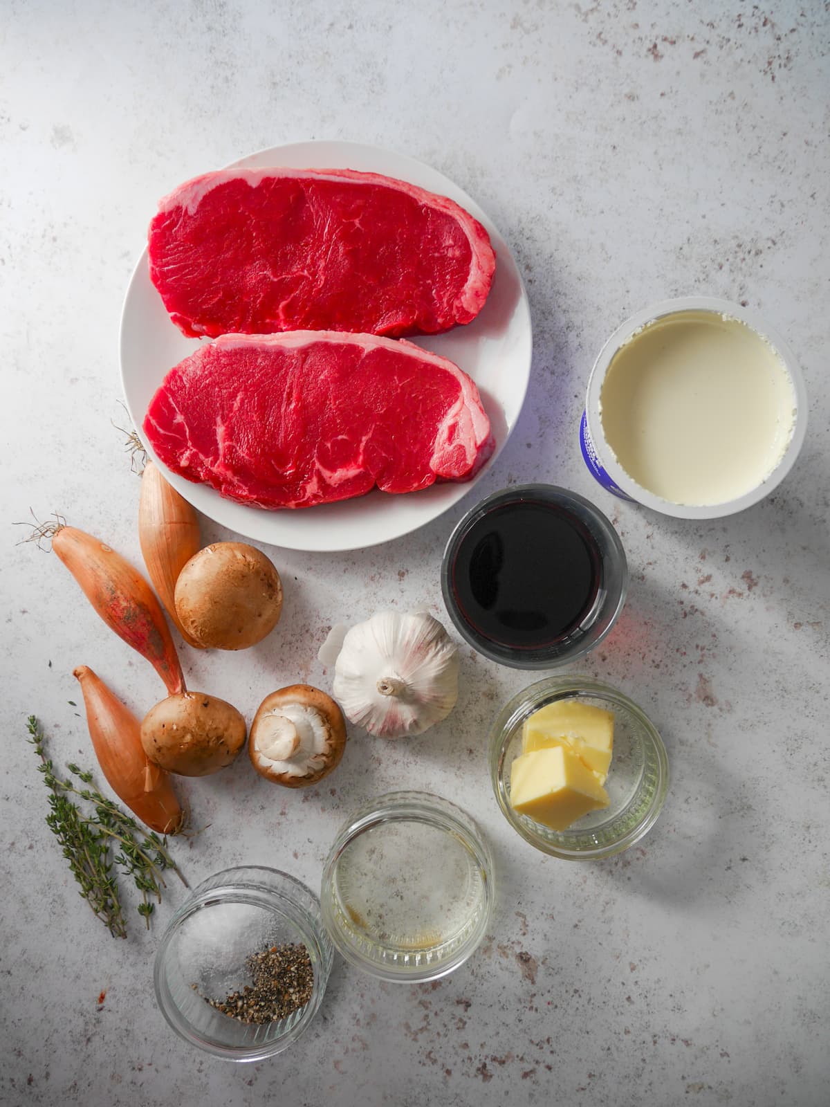 Individual recipe ingredients for sirloin steak, and red wine and mushroom sauce.