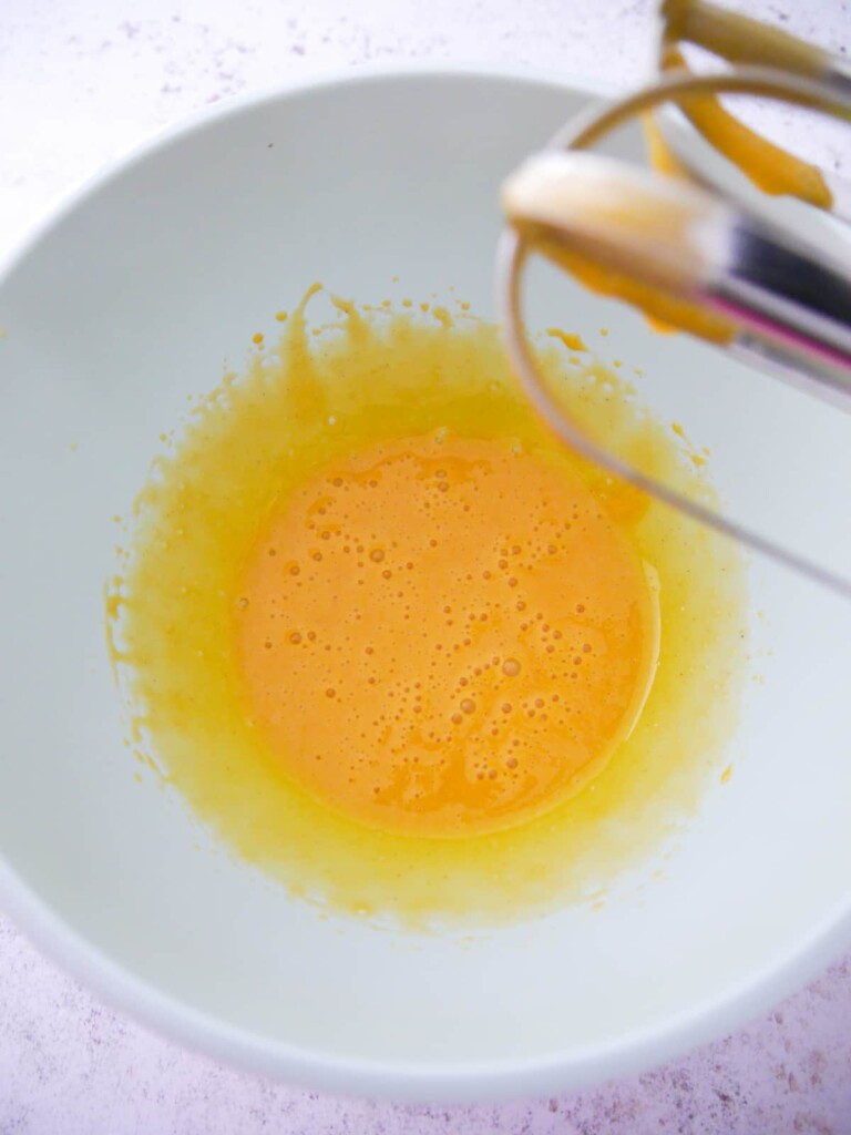A bowl of whisked egg white and mustard.