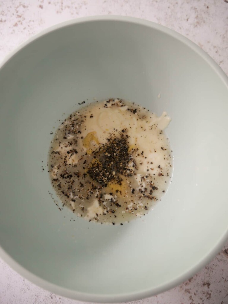 A bowl filled with salad dressing ingredients for a celeriac remoulade.