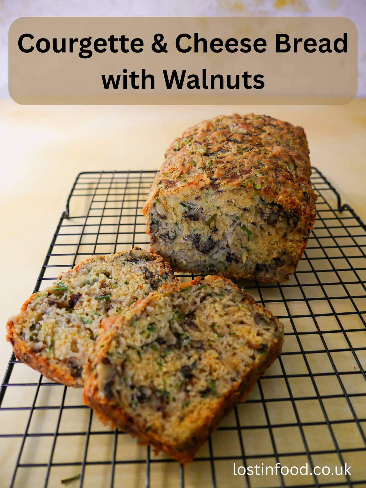 Pinnable image with recipe title and courgette and cheese bread with walnuts on a wire cooling rack with two slices cut from it.