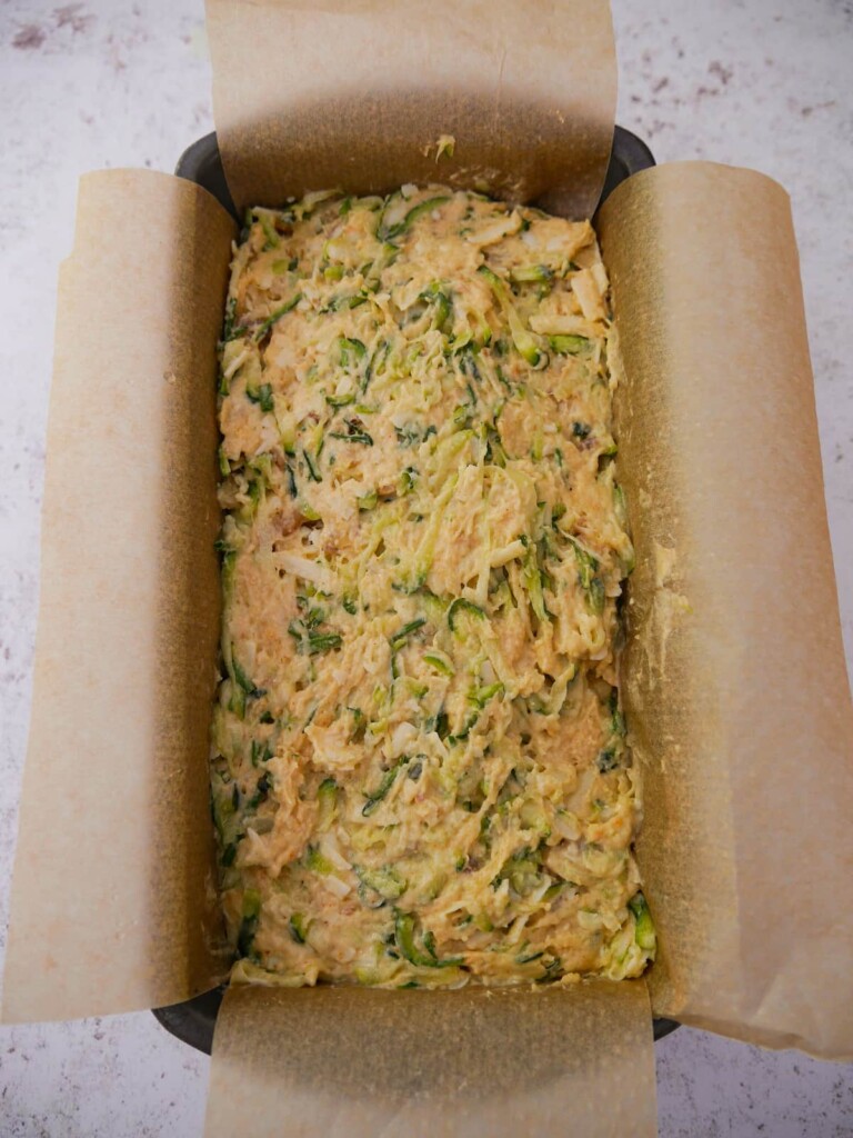 A line loaf tin fill with courgette and cheese bread dough.