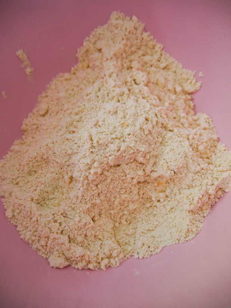 A mixing bowl filled with a flour and butter rubbed breadcrumb like mixture.