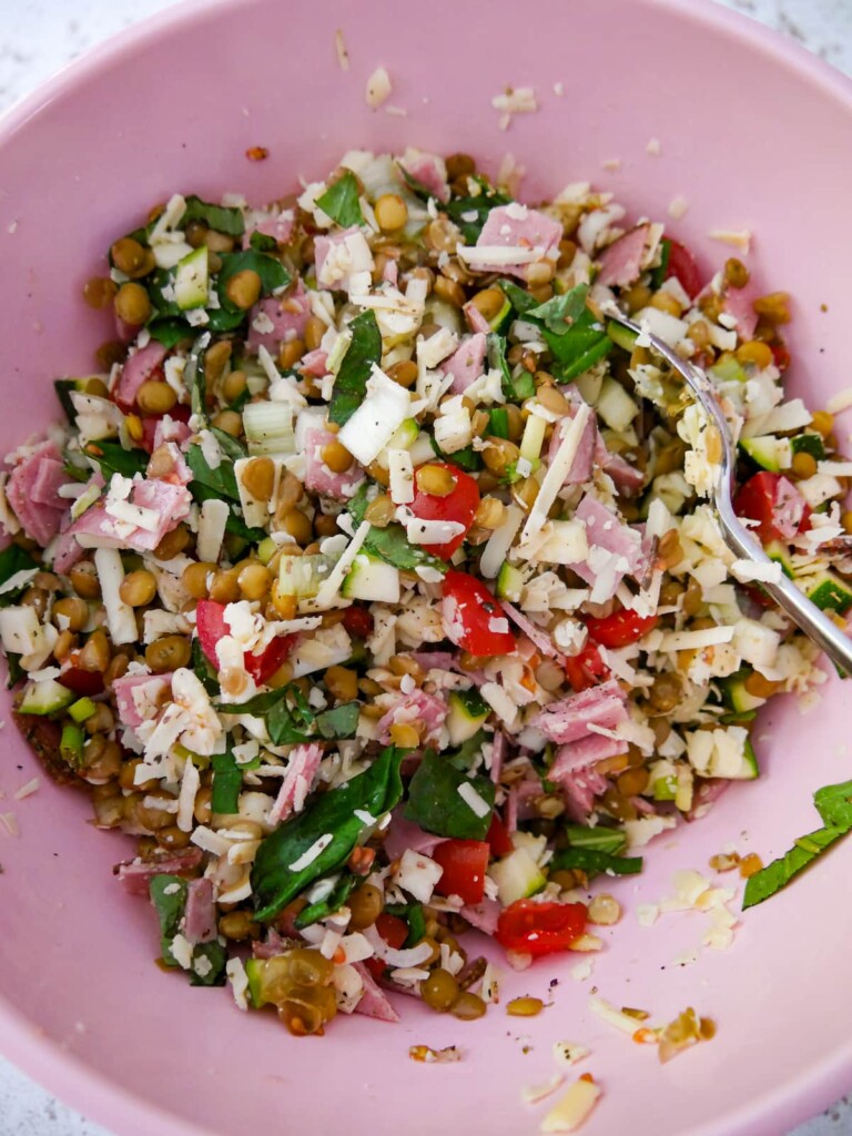 A pink bowl containing the lentil and vegetable mixture for stuffed peppers.