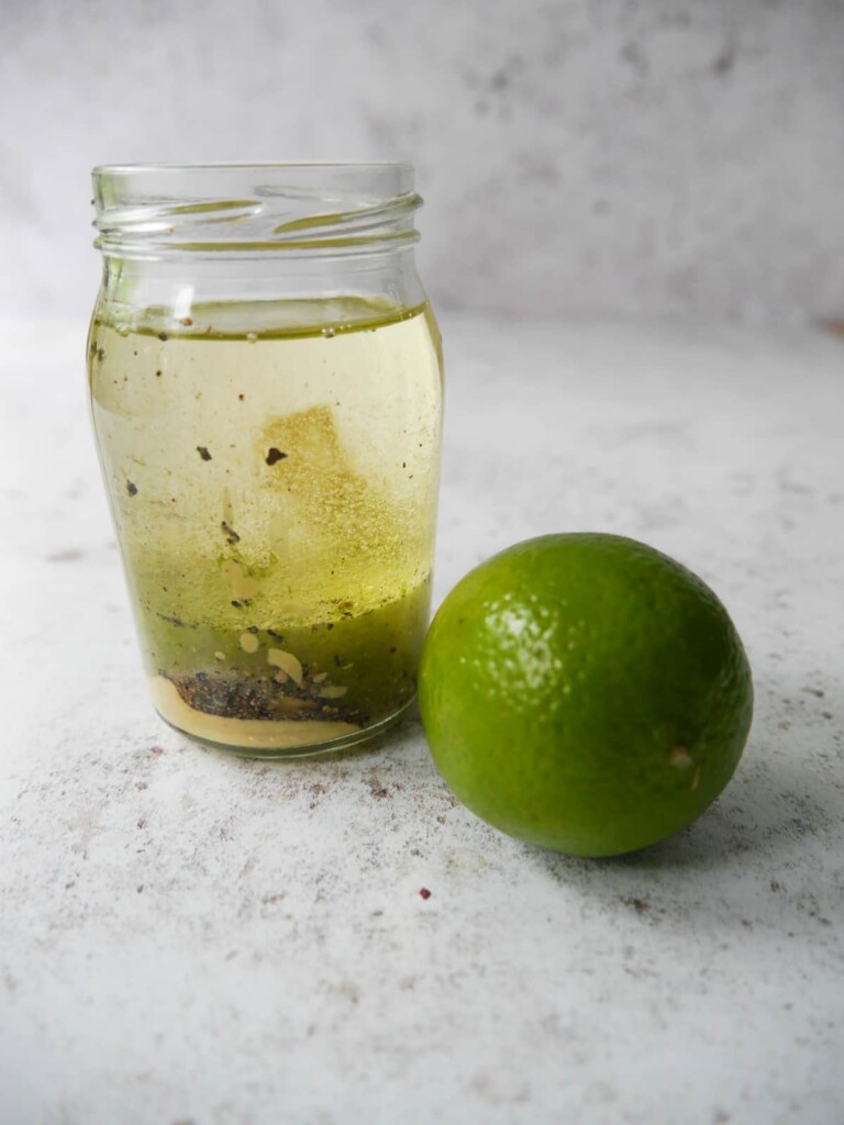 A jar filled with ingredients for zesty lime vinaigrette dressing.