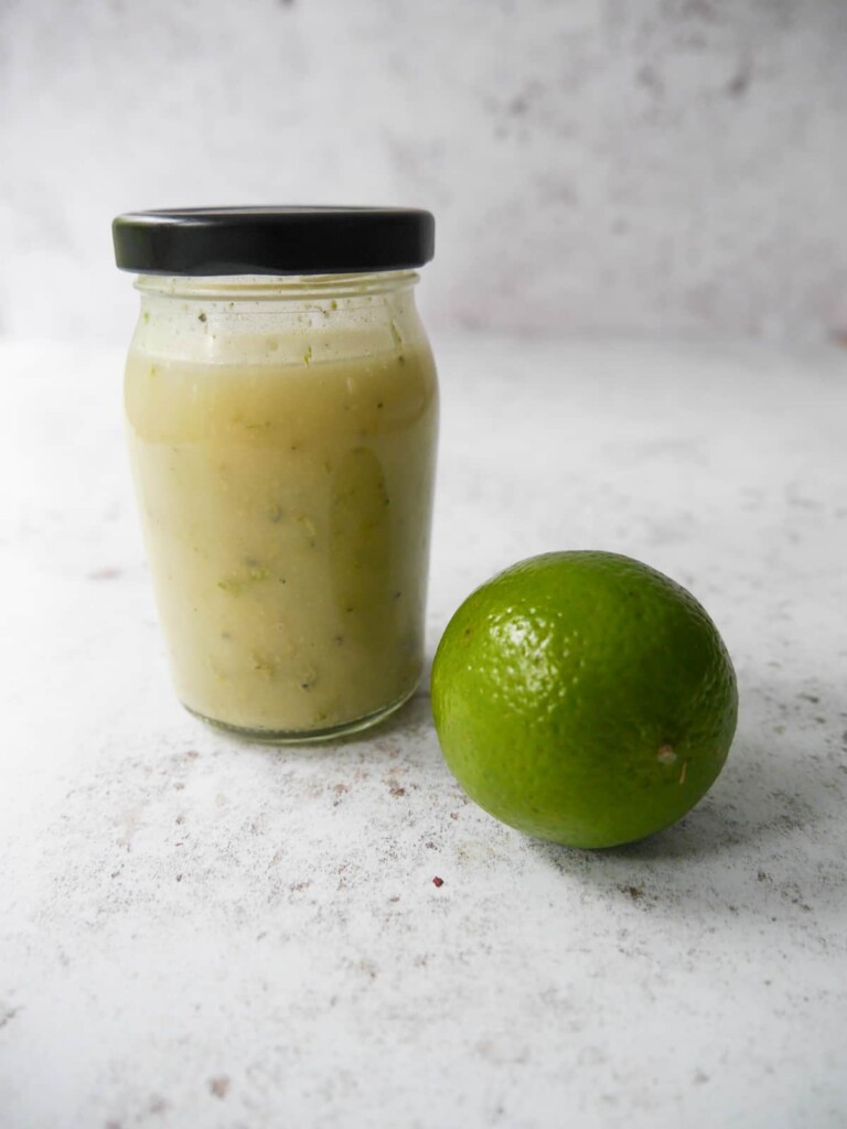 A lidded jam jar filled with lime vinaigrette dressing.