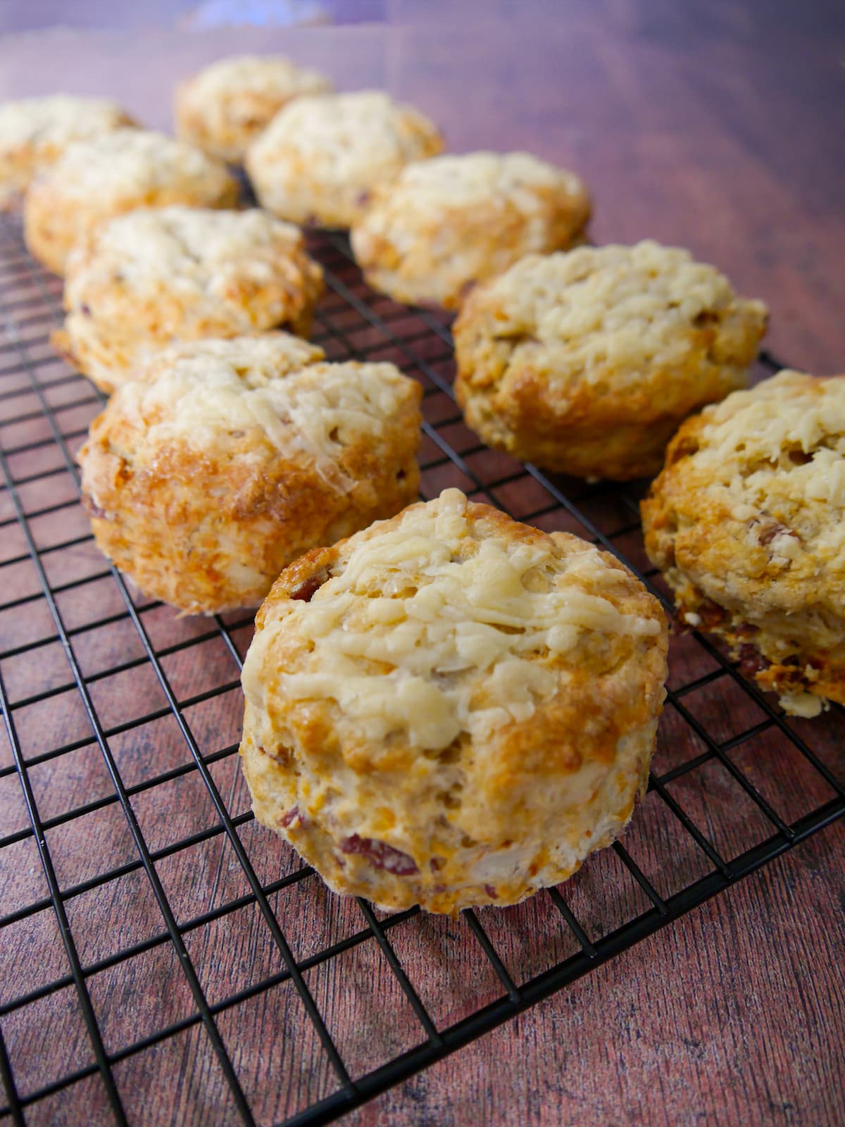 Freshly baked cheese bacon tomato scones set on a wire cooling rack.