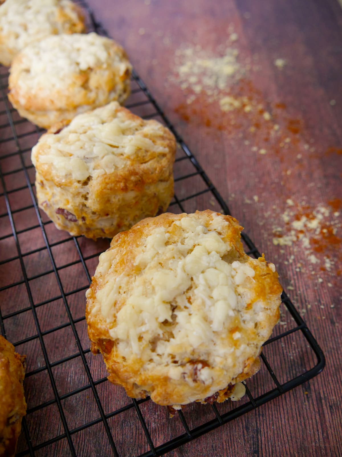 Freshly baked cheese bacon tomato scones set on a wire cooling rack.