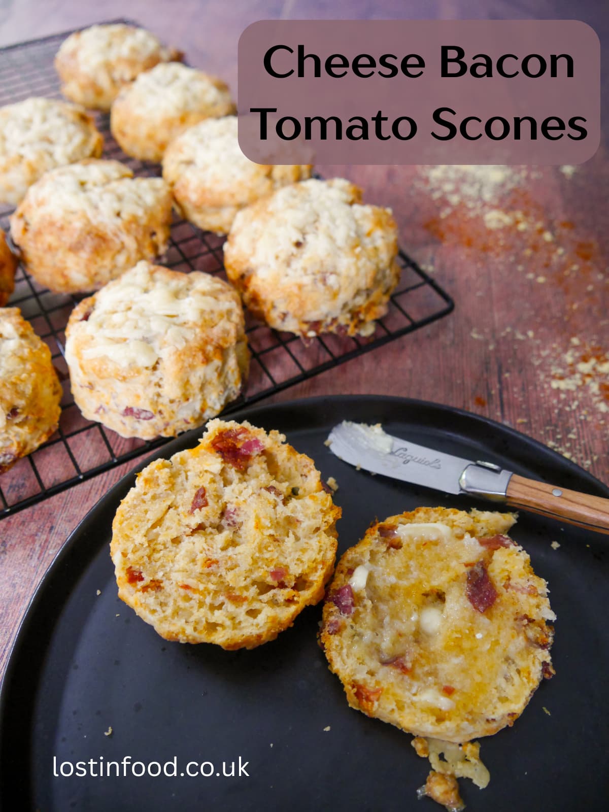 Pinnable image with recipe title and a plate with a cut and buttered cheese bacon tomato scone on top, with a wire rack of scones set alongside.