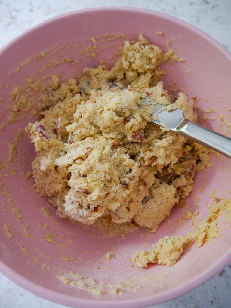 Cheese bacon tomato scone dough being brought together with a flat kitchen knife.