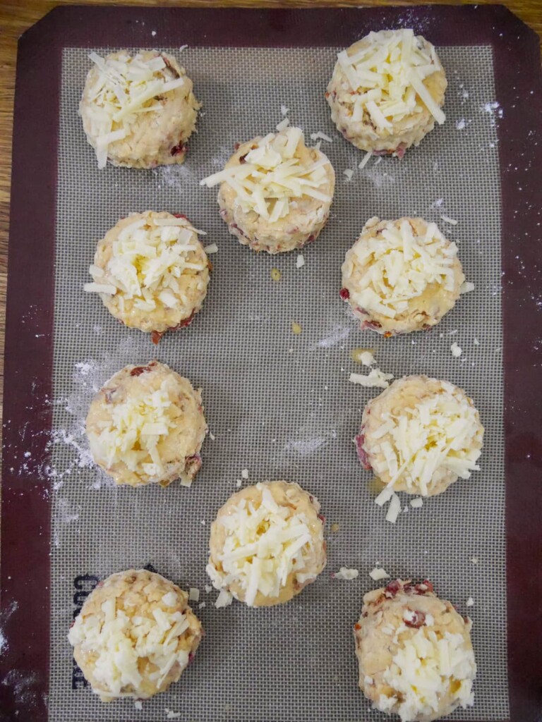 A lined baking sheet topped with freshly cut cheese bacon tomato scones.