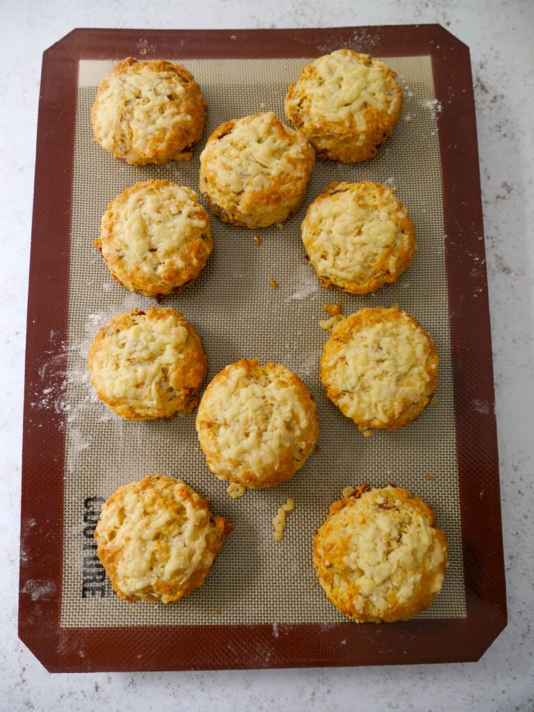 A lined baking sheet topped with freshly baked cheese bacon tomato scones.