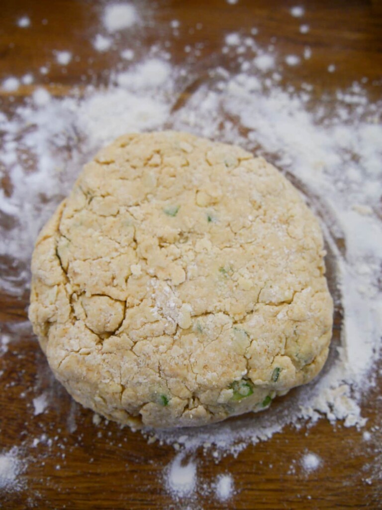 A ball of cheese and jalapeno scone dough set on a floured board.