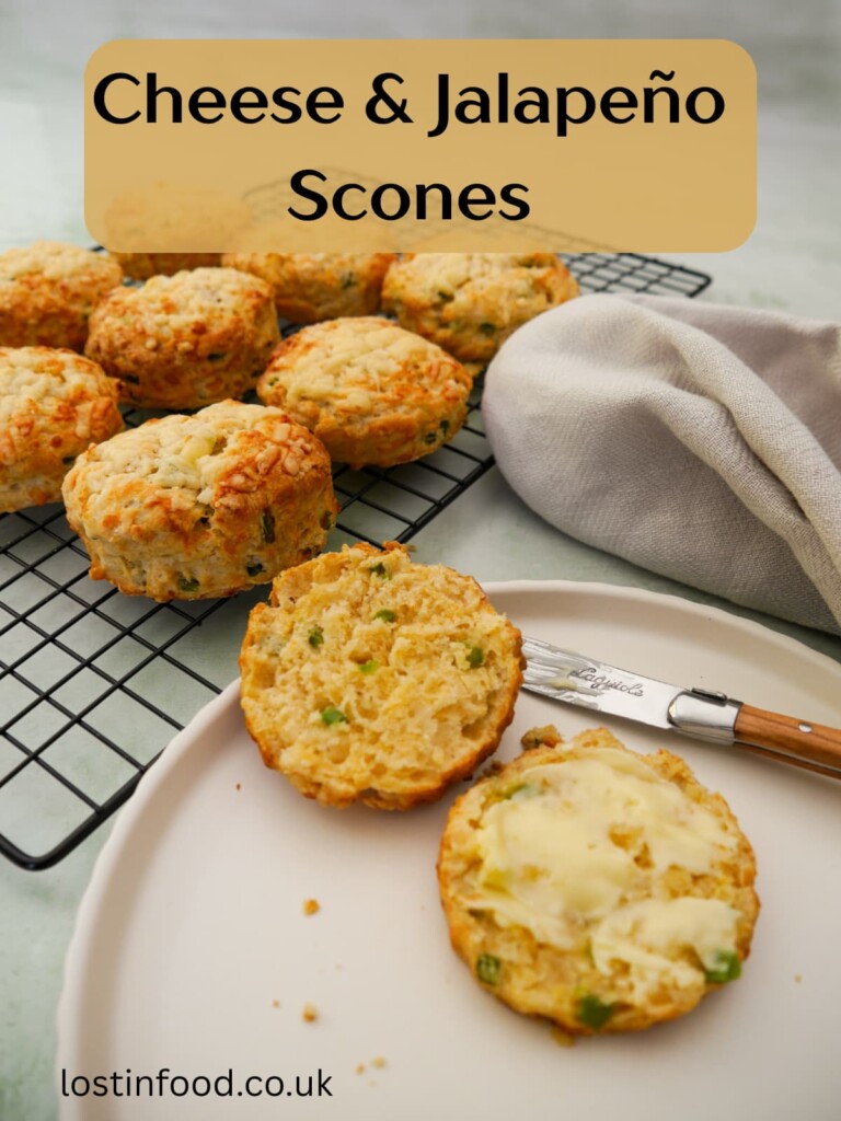 Pinnable image with recipe title and a plate topped with a cheese and jalapeno pepper scone, cut in half and buttered. A wire rack of scones is set alongside.