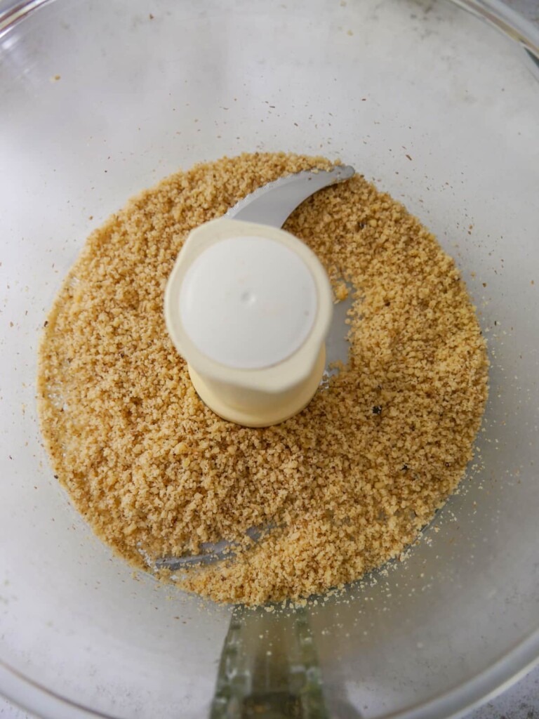 A food processor bowl of blitzed walnuts (walnut meal).