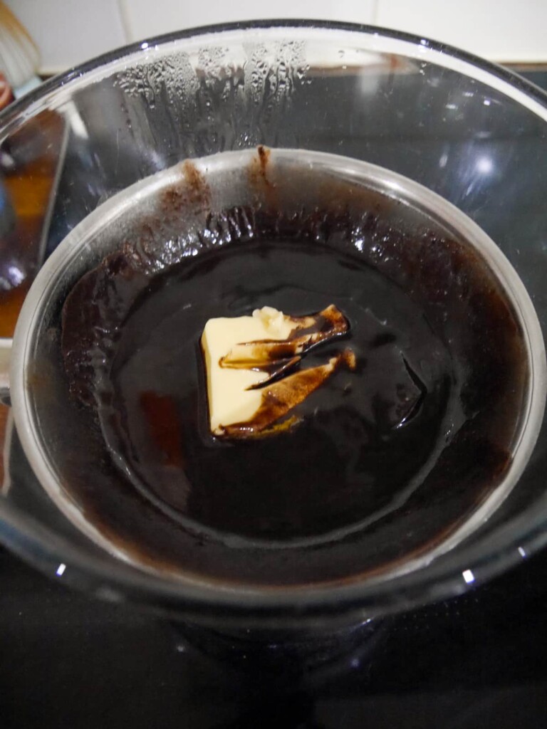 A glass bowl of dark chocolate and butter, set over a pan of boiling water to melt (known as a bain marie).