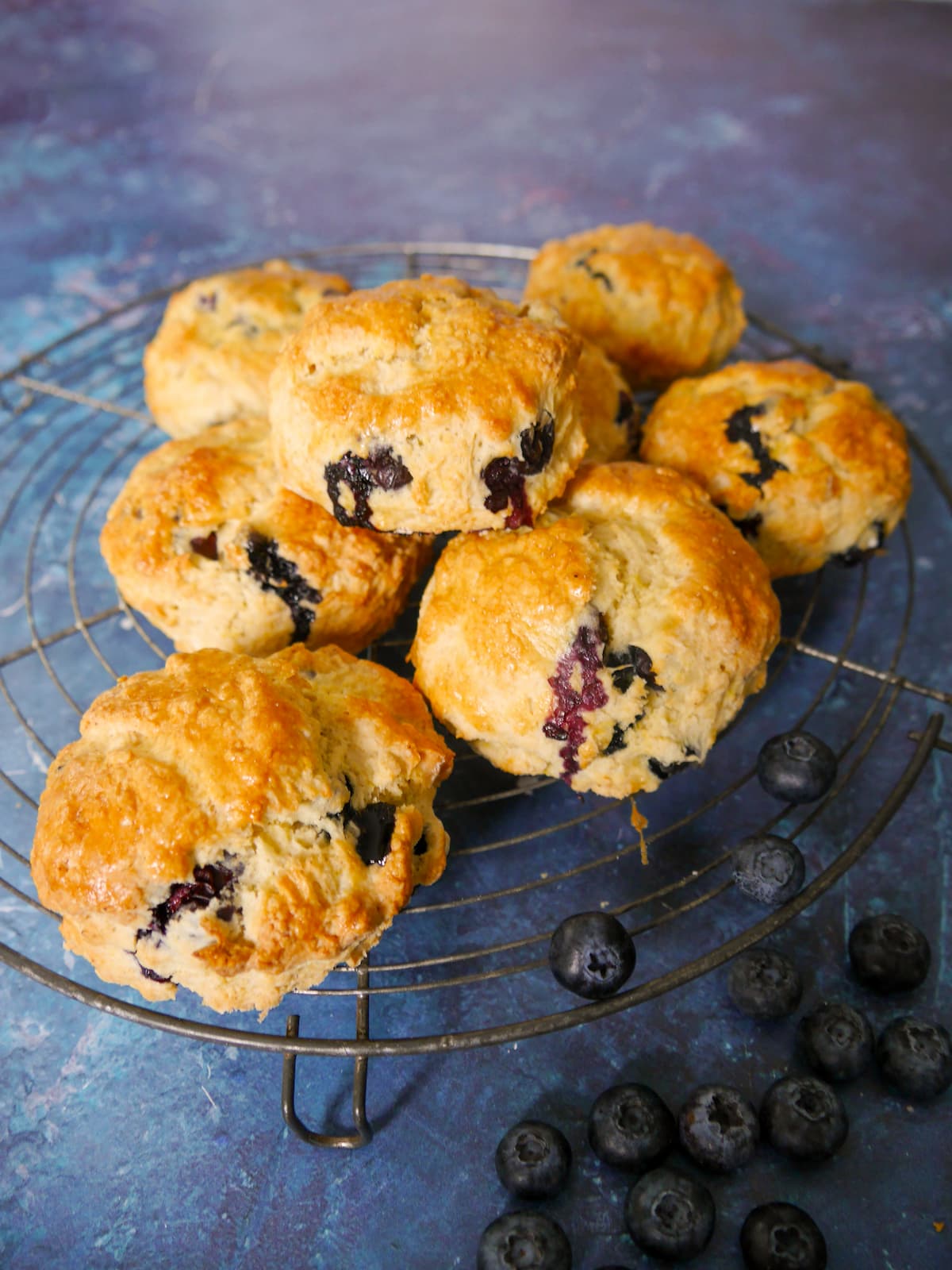 A wire rack topped with lemon and blueberry scones.