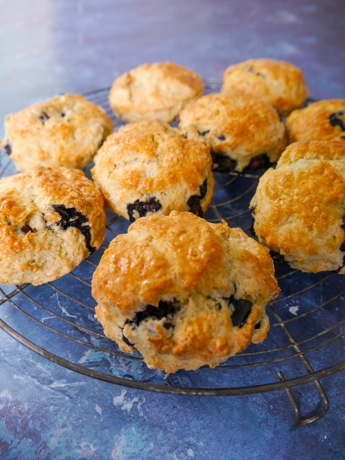 A wire rack topped with lemon and blueberry scones.