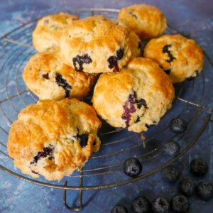 A wire rack topped with lemon and blueberry scones.