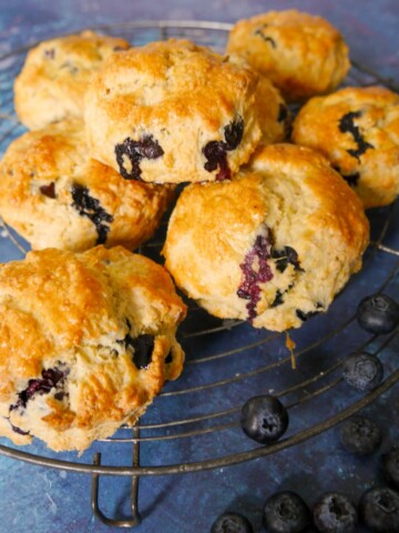 A wire rack topped with lemon and blueberry scones.