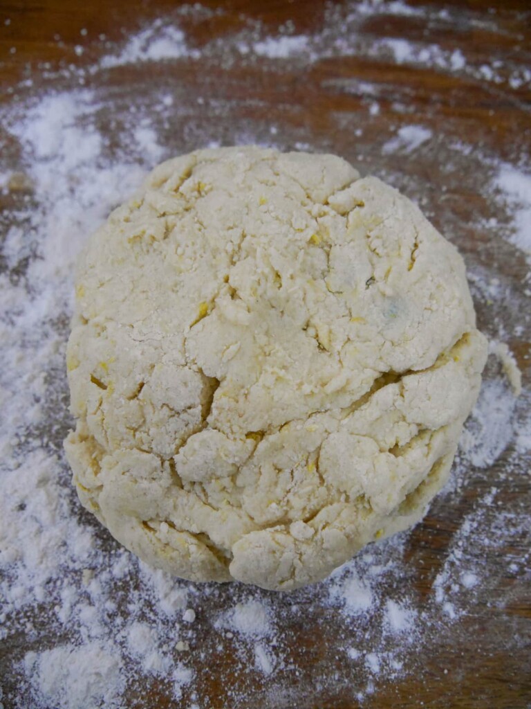 A ball of lemon and blueberry scone dough on a floured surface.