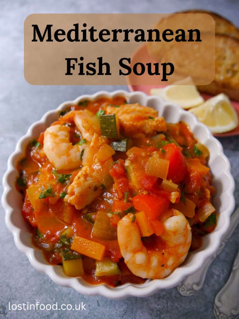 Pinnable image with recipe title and a bowl of Mediterranean fish soup served with toasted sourdough and wedges of lemon.