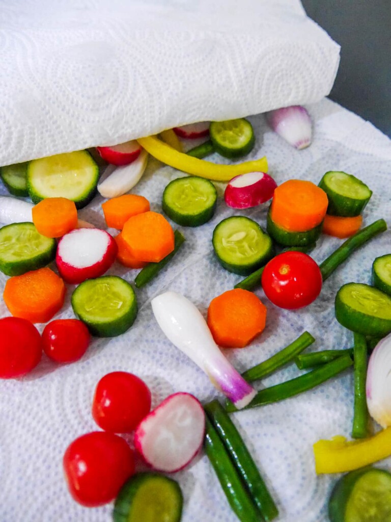 A variety of salted and washed sliced vegetables being dried on kitchen paper.