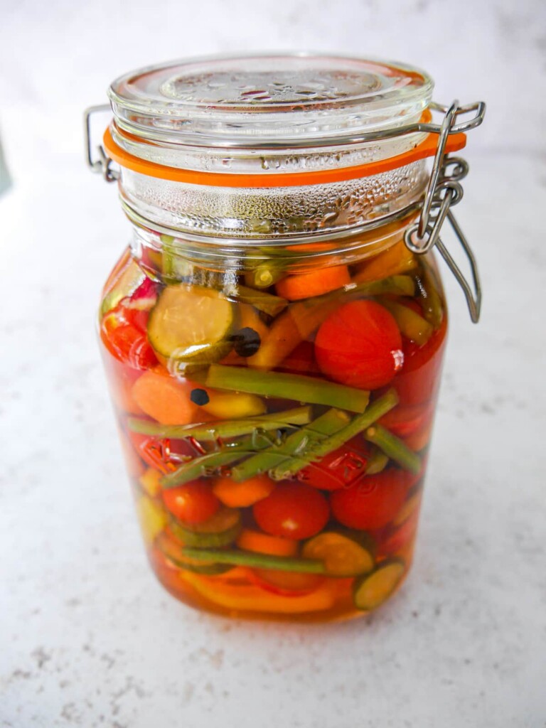 A large mason jar filled with sliced vegetables and vinegar.